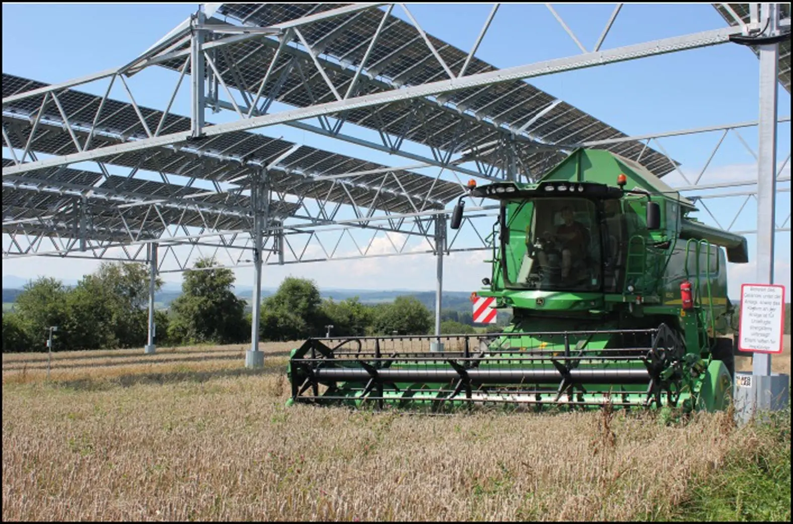 a farm combine near solar energy equipment